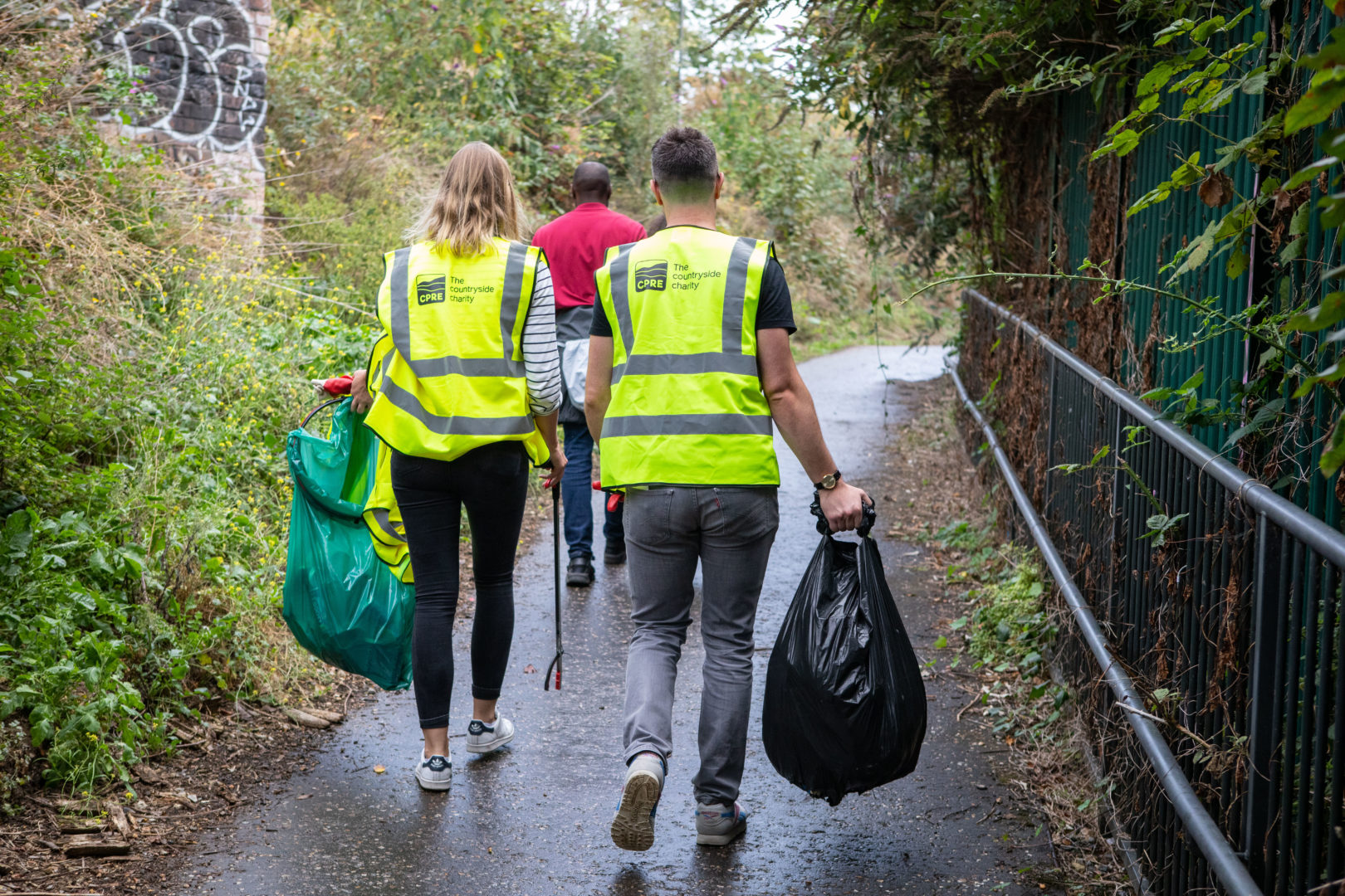 ers on litter pick walking away from camera with sacks of litter